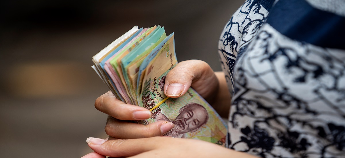Close up of someones hand holding a wad of Vietnamese dong bank notes