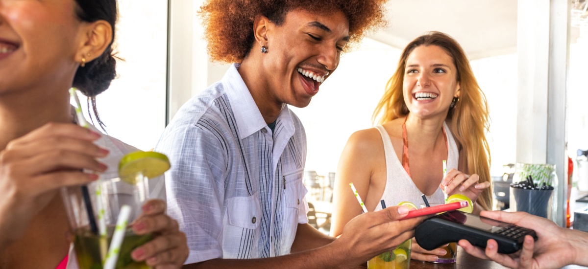 smiling-man-paying-at-beach-bar-with-phone