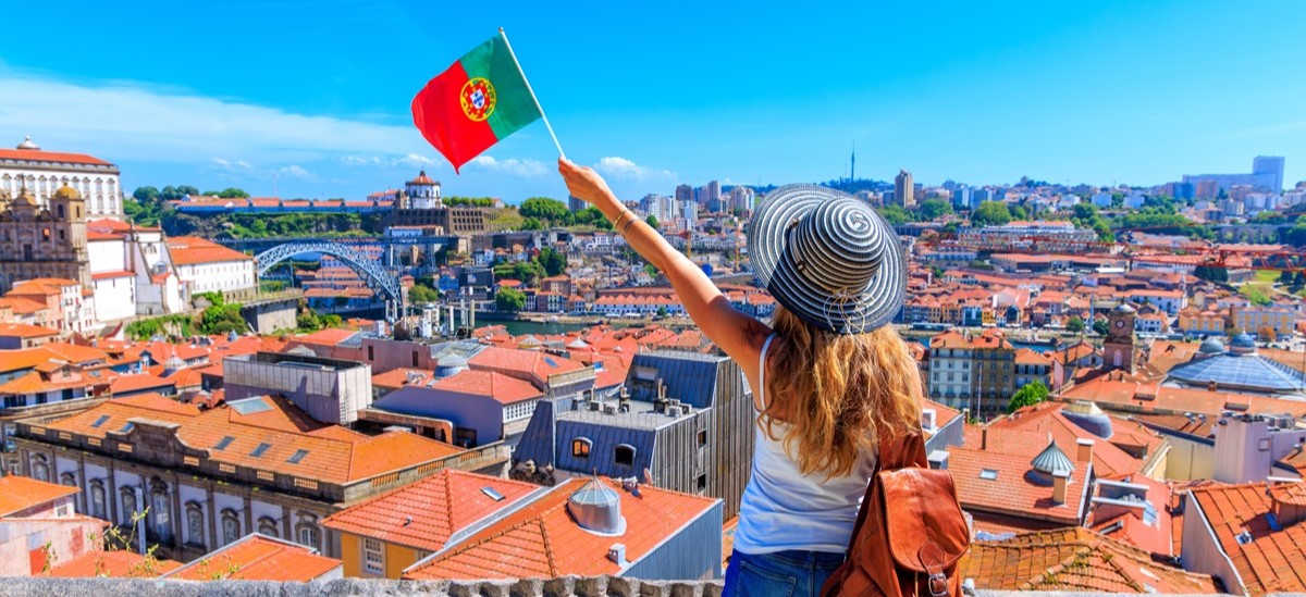 Woman waving Portuguese flag looking at city of Porto