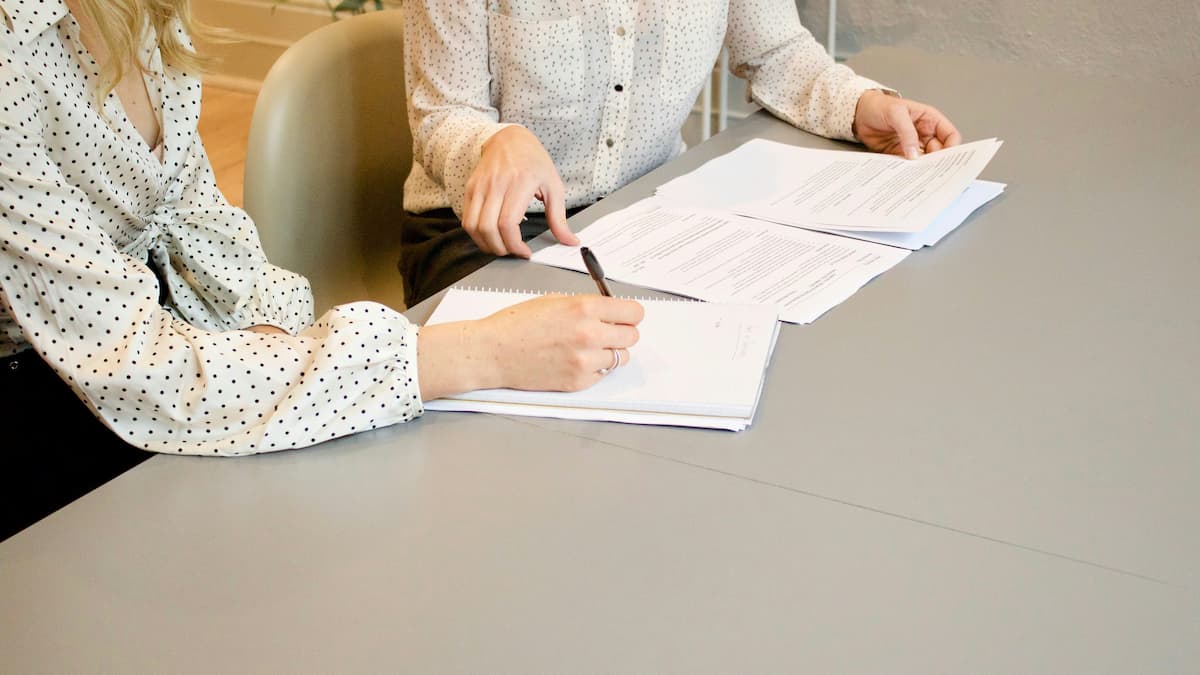 Zwei Personen diskutieren offizielle Dokumente an einem Tisch
