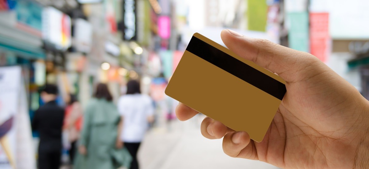 Close up of a hand holding a card in front of blurred shopping street in Asia