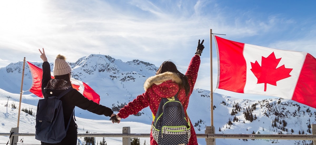 Two people in snow in Canada with Canadian flag