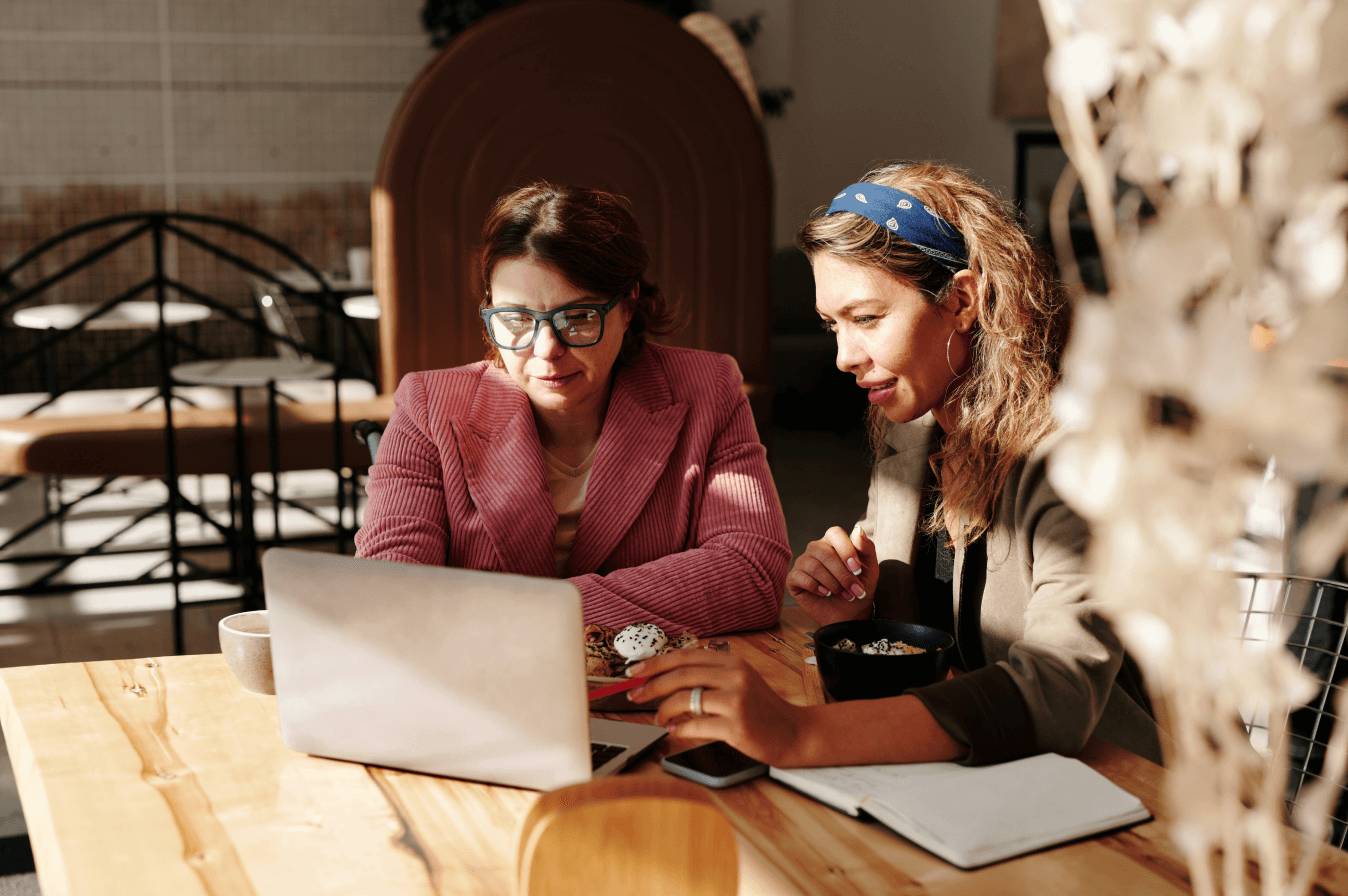 2 people sitting at table looking at a laptop